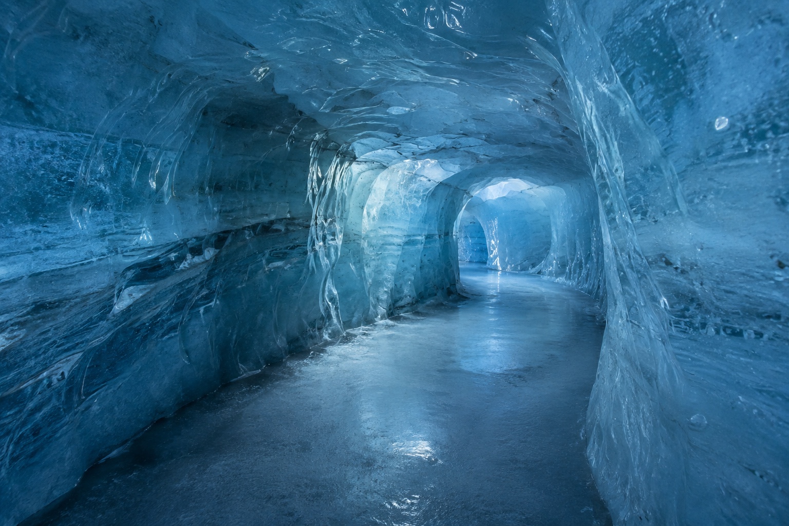 Blue-lit ice cave tunnel carved into the glacier at the Glacier Palace near Matterhorn Glacier Paradise